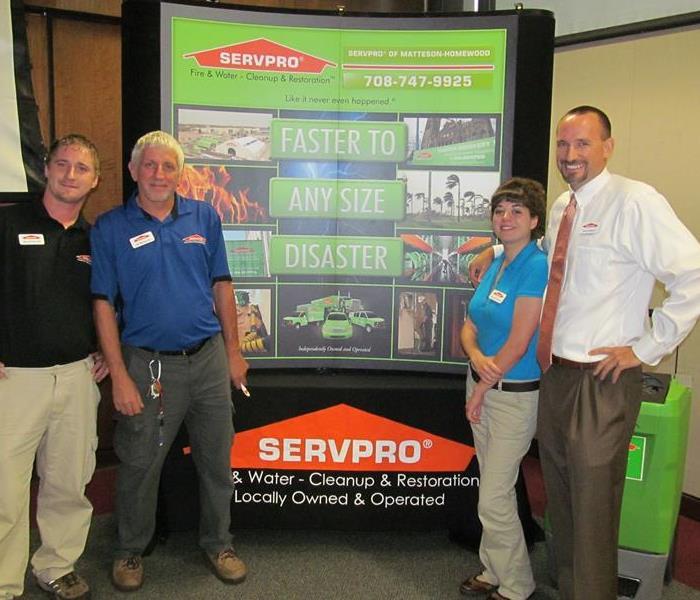 Four people standing in front of a large SERVPRO banner