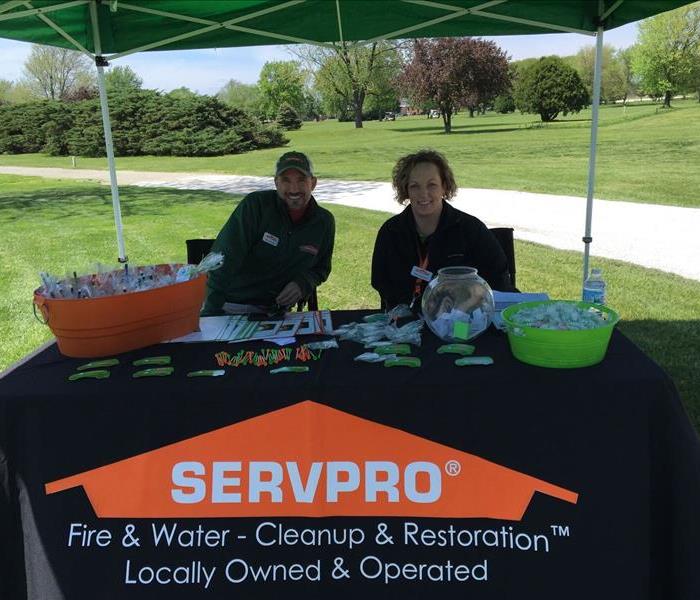 Male and female employee sitting at a table with a SERVPRO table cloth over the table