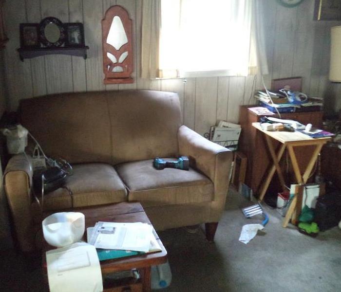 Tan couch and various household items in a room damaged by a fire