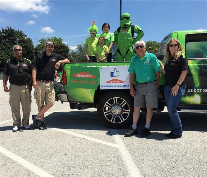 SERVPRO representatives, children, and a green storm trooper standing around SERVPRO green truck in a parking lot